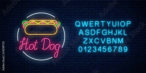 Neon hot dog cafe glowing signboard with alphabet on a dark brick wall background. Fastfood light billboard sign.