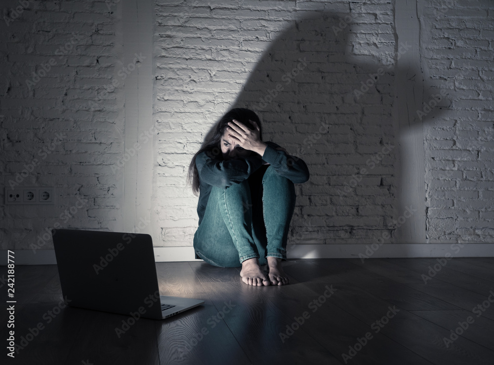 Woman suffering Internet cyber bullying and harassment feeling lonely looking afraid at laptop Woman suffering Internet cyber bullying and harassment feeling lonely looking afraid at laptop