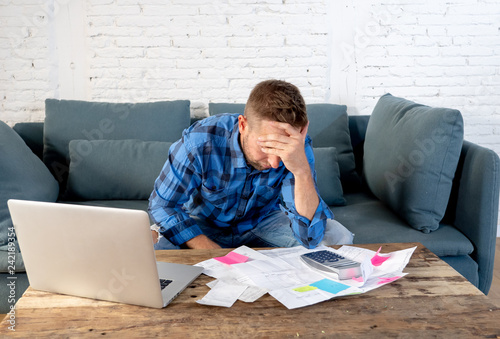 Fotografie Angry man paying bills managing finances feeling desperate and hopeless with too