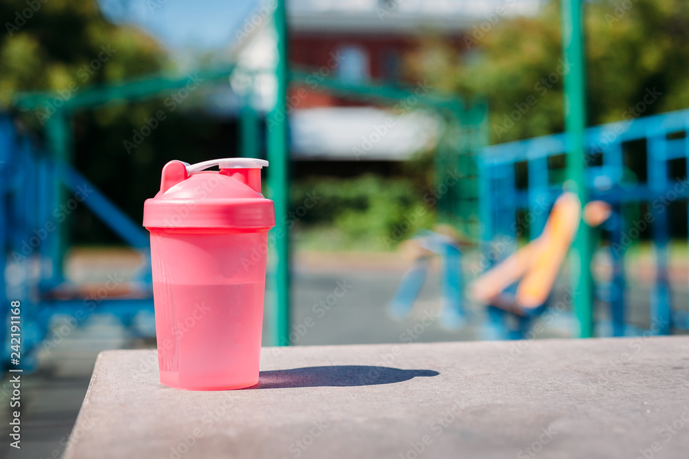 Obraz premium Closeup of glass with cold illuminating cool water for sports training on a hot sunny day. concept of healthy lifestyle. Fitness
