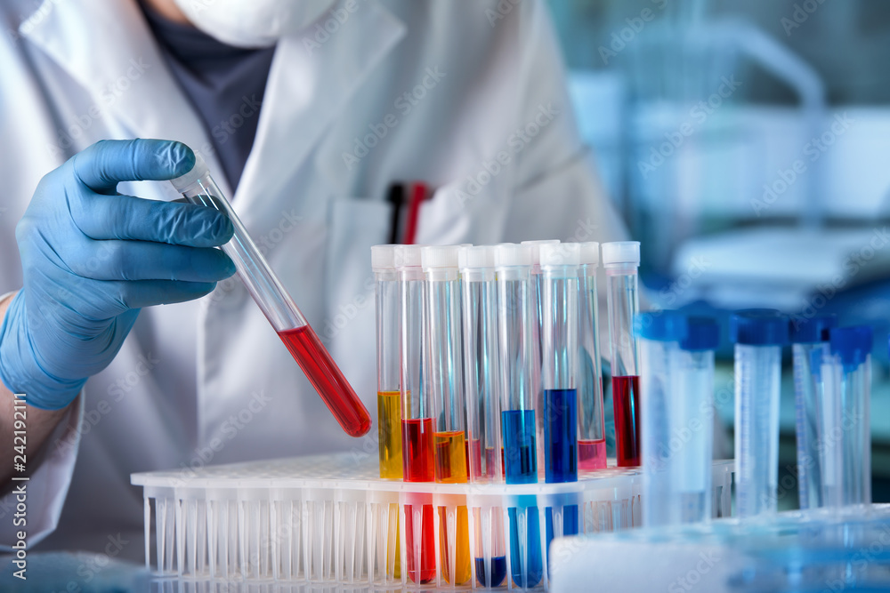 biochemical engineer working with fluid tubes in the laboratory / researcher studying samples of liquids in the lab 