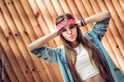 Modern young woman in red bandage and round sunglasses posing at camera.Lifestyle,trendy concept.