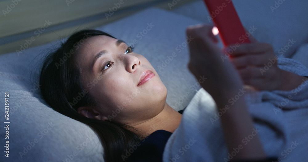 Woman watch on mobile phone and lying on bed at night Woman watch on mobile phone and lying on bed at night