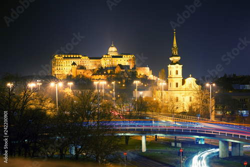 Night view of Saint Catherine of Alexandria Church and Royal Palace of Buda. Road junction and blurred transport lights. Budapest, Hungary