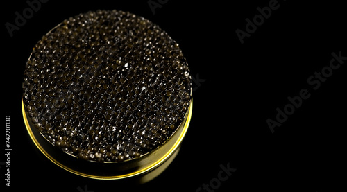 Black caviar closeup. Black caviar in tin can on black background. Delicatessen