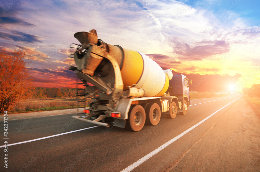 Concrete mixer truck on the countryside road against sky with sunset - obrazy, fototapety, plakaty 