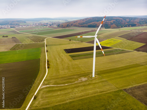 Aerial view of a moving wind turbine in a rural area