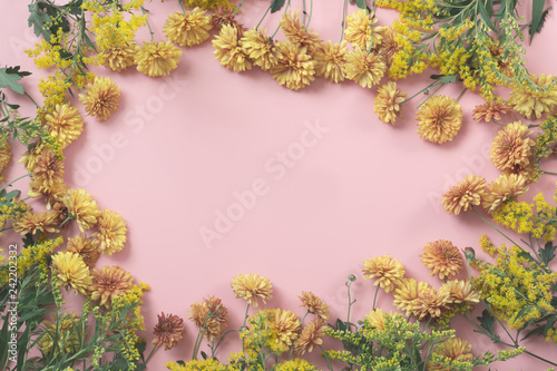 Golden-daisy flowers as border on pastel pink background. Floral pattern.