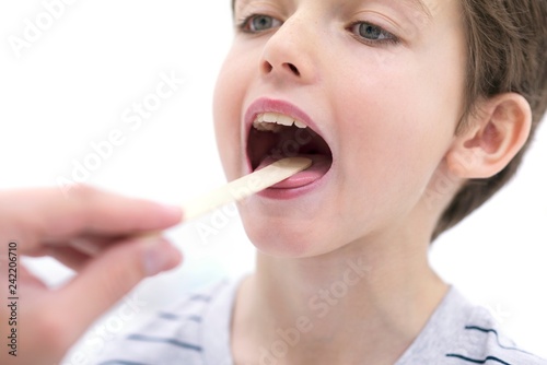 Boy with mouth open and tongue depressor photo