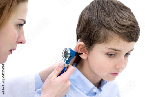 Doctor examining boy's ear with otoscope photo