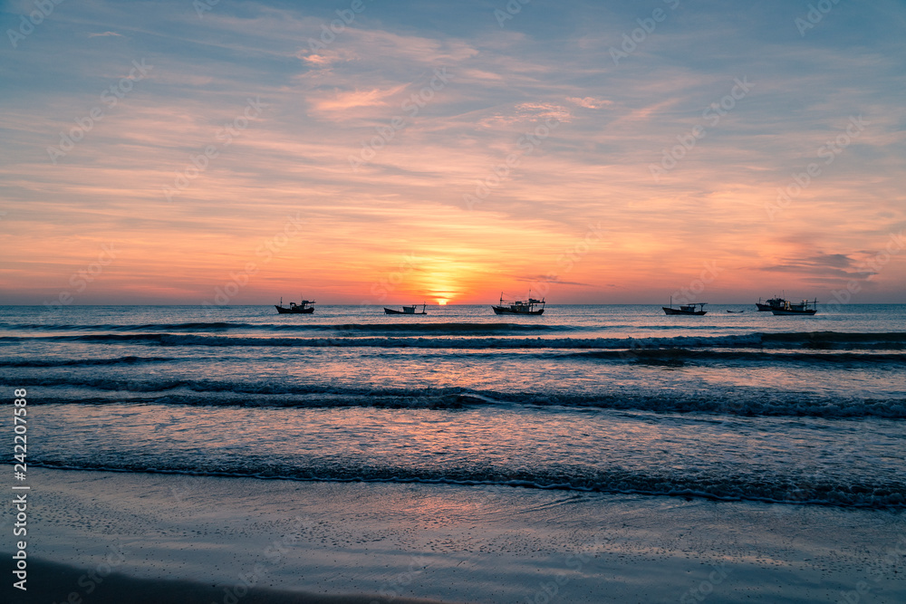Sunrise on paradise beach with fishing boat