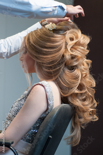 Process of creating evening hairstyles for a girl with long blond hair by a master hairdresser at a beauty marathon in Chelyabinsk, Hotel Redisson Blue, December 2, 2018