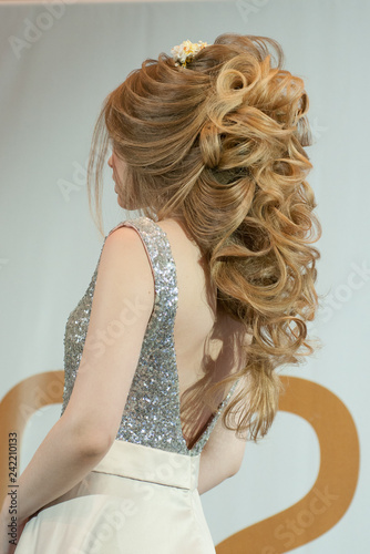 evening hairstyle on a model girl with long blond hair and in an evening white dress at a beauty marathon in Chelyabinsk, Hotel Redisson Blue, December 2, 2018