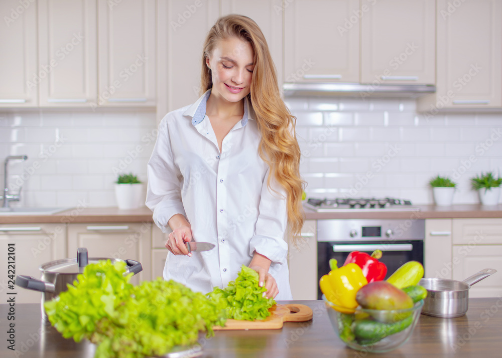 Beautiful girl in a white shirt prepares healthy food from vegetables Beautiful girl in a white shirt prepares healthy food from vegetables
