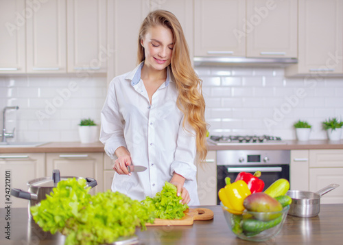 Beautiful girl in a white shirt prepares healthy food from vegetables