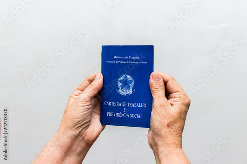 hands of Caucasian senior woman holding work book, Brazilian social security document