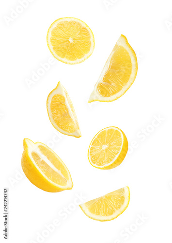 Cut fresh lemons falling against white background