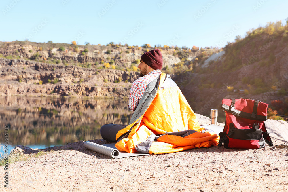Male camper with sleeping bag in wilderness Male camper with sleeping bag in wilderness