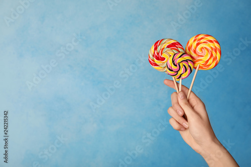 Woman holding yummy candies on color background. Space for text