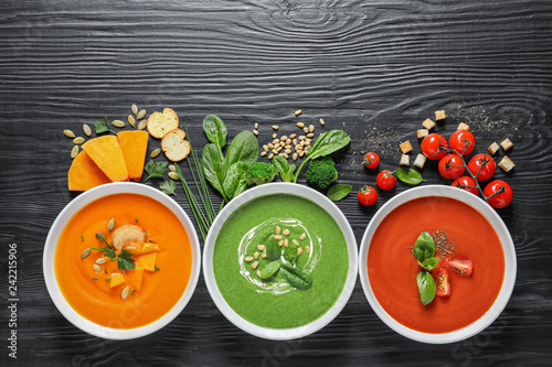 Flat lay composition with various soups and ingredients on wooden background. Healthy food