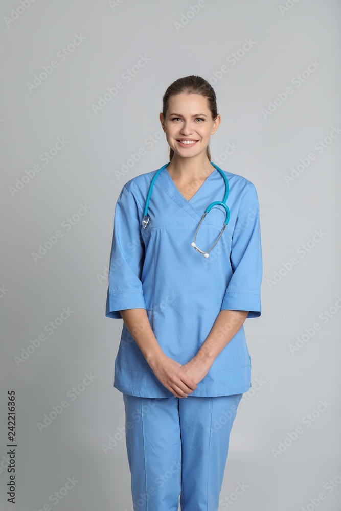 Portrait of young medical assistant with stethoscope on color background