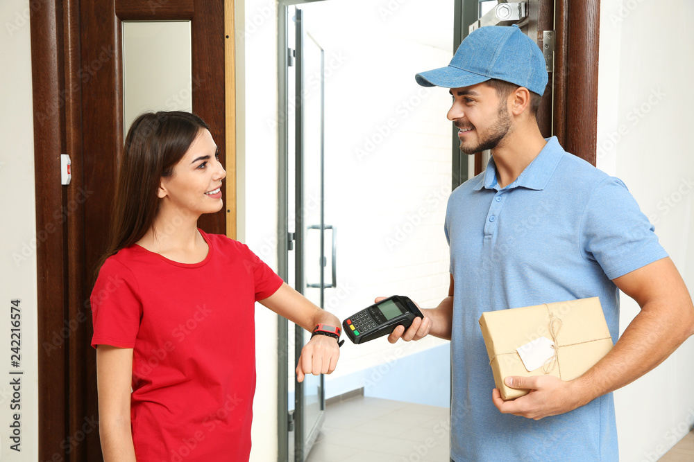 Woman with smartwatch using terminal for delivery payment indoors Woman with smartwatch using terminal for delivery payment indoors