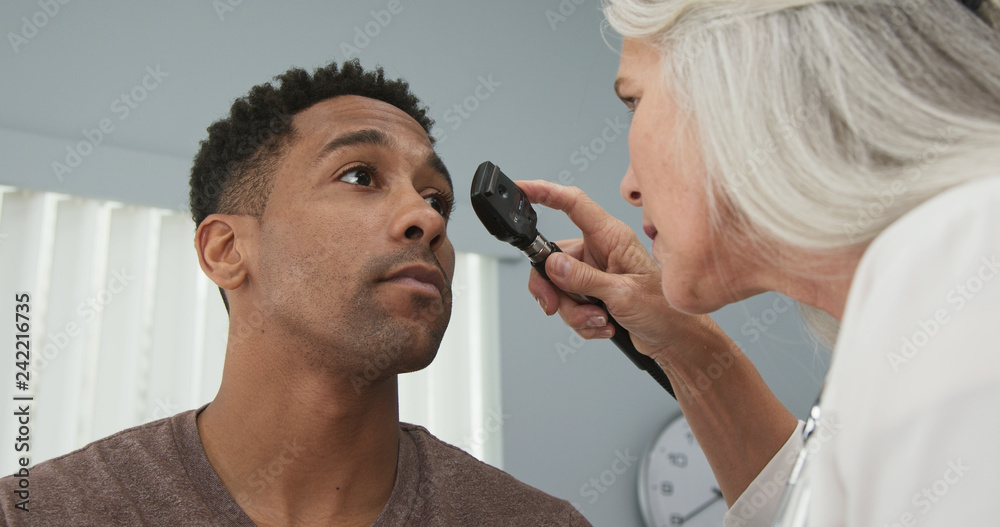 Young black male patient having his eyes checked by senior female