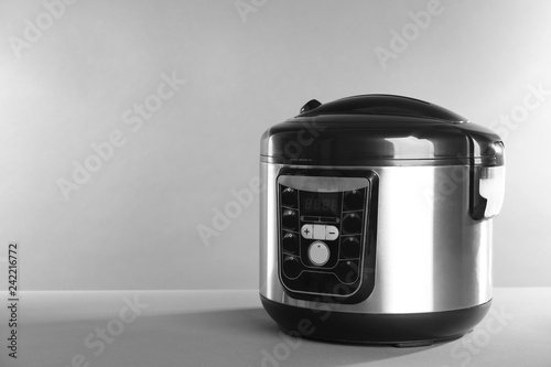 Modern powerful multi cooker on table against grey background. Space for text