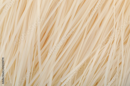 Raw rice noodles as background, closeup. Delicious pasta