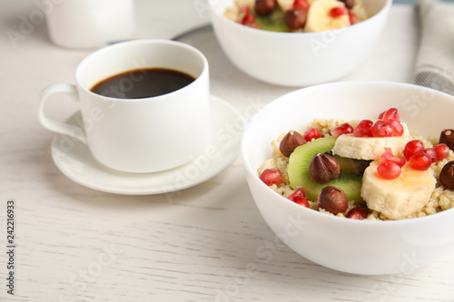 Quinoa porridge with hazelnuts, kiwi, banana and pomegranate seeds served for breakfast on white wooden table