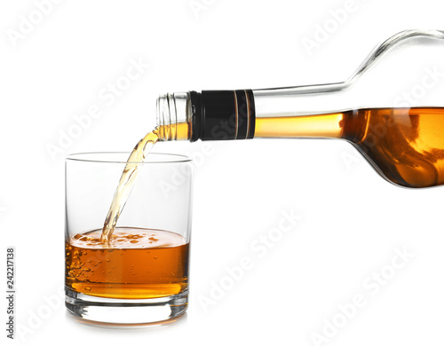 Pouring expensive whiskey into glass on white background