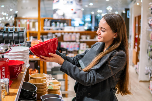 young beautiful woman choosing dinner utensil plate dishes in a store supermarket shop. photo