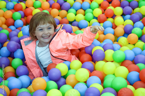 The child is a part of plastic balls. The girl is playing and having fun. The concept of a happy, carefree childhood. Entertainment and recreation with children.