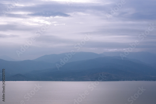 abstract mystic foggy mountains silhouette near big lake calm water surface background wallpaper pattern scenery landscape