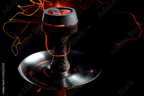 Shisha bowl with craft tobacco and red coil with hookah smoke background.