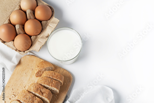 Glass bowl, milk, eggs, bread plates of a white background.