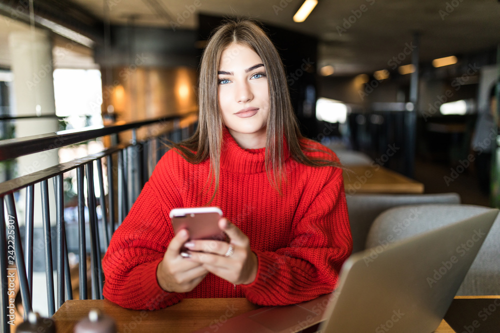Young Woman hand using smart phone and cup of coffee her working on laptop in coffee shop, freelance lifestyle. Young Woman hand using smart phone and cup of coffee her working on laptop in coffee shop, freelance lifestyle.