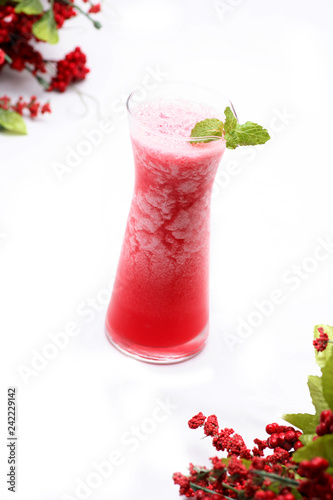 Watermelon juice blended in a clear glass on a white background There is a branch of cherry trees.soft focus.
