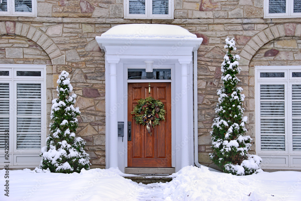 Obraz premium stone fronted house with snow and wreath on front door