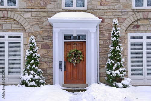 stone fronted house with snow and wreath on front door © Spiroview Inc.