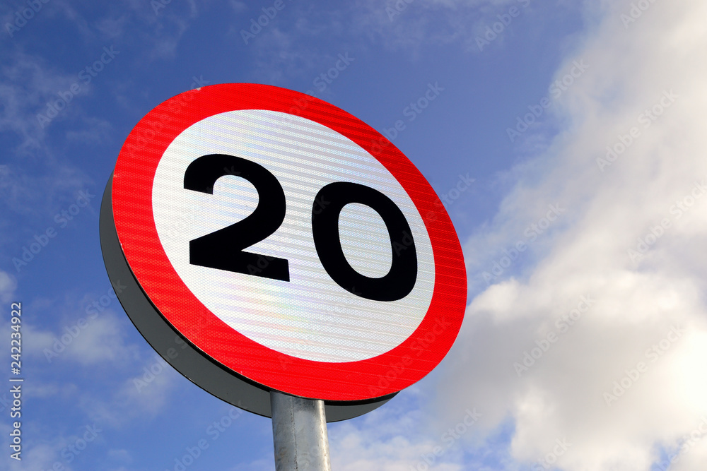 Twenty mile per hour street sign with blue skies in background.