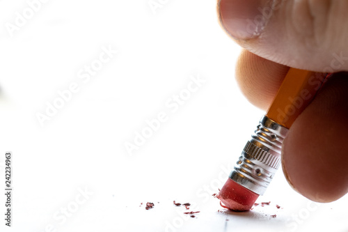 Pencil with finger tips erasing mistake made on white paper