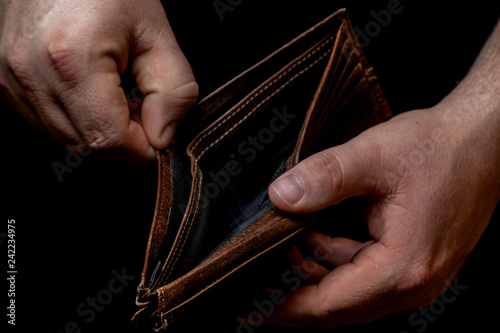 Male hands holding an empty wallets on a black background photo