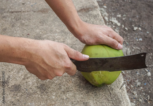 close up man use big knife to peel green fresh coconut