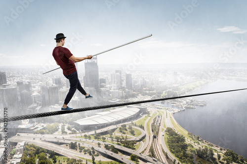 Brave ropewalker on cable. Mixed media photo