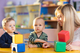 Child boy together with mother playing educational toys at sunny day in nursery