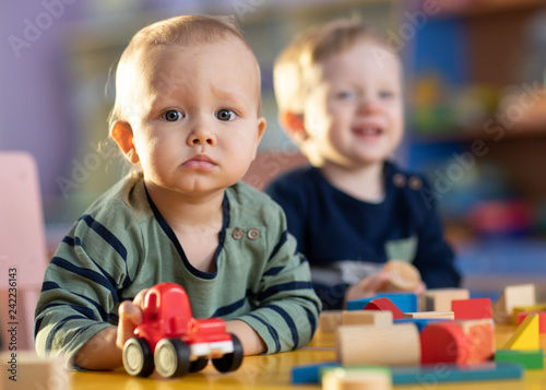 Baby boys with toy car and building blocks in kindergarten