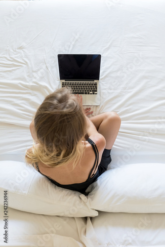 Blonde woman with her laptop on the bed