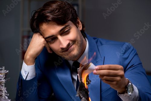 Businessman burning the evidence late in office photo