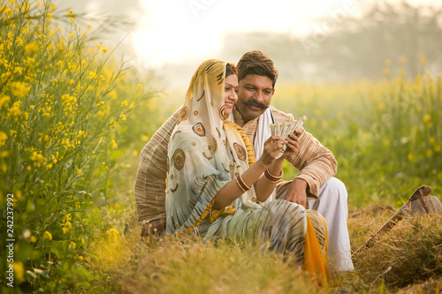 Rural couple holding Indian rupee notes in agriculture field